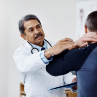 Doctor examining patient’s neck to recommend non-surgical neck pain treatment.