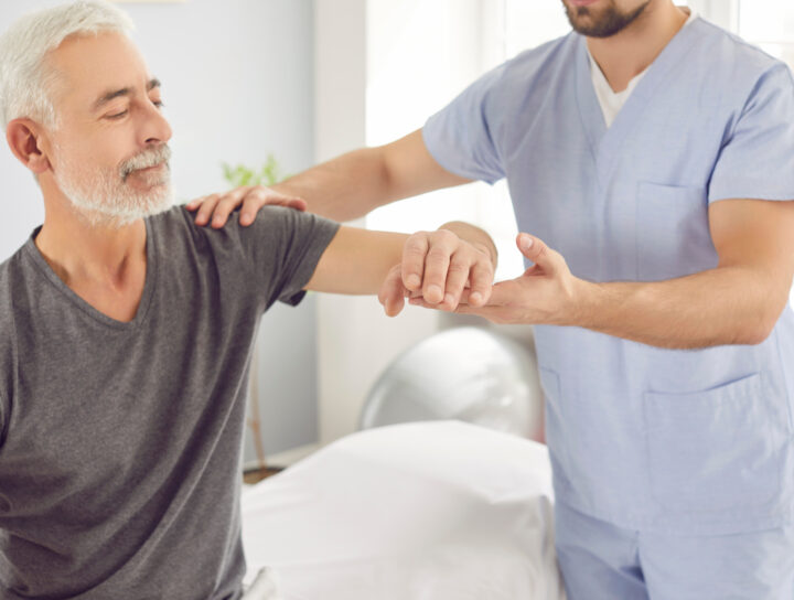 Senior man receiving physical therapy from a therapist during outpatient rehabilitation to improve strength and mobility after surgery