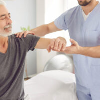 Senior man receiving physical therapy from a therapist during outpatient rehabilitation to improve strength and mobility after surgery