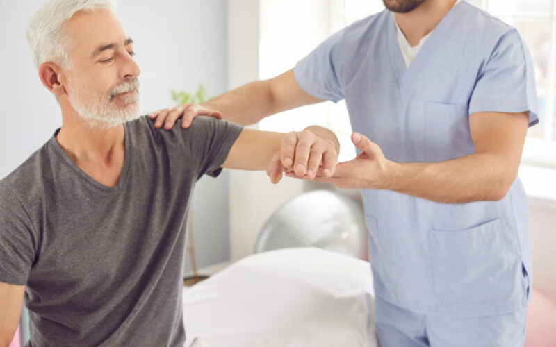 Senior man receiving physical therapy from a therapist during outpatient rehabilitation to improve strength and mobility after surgery