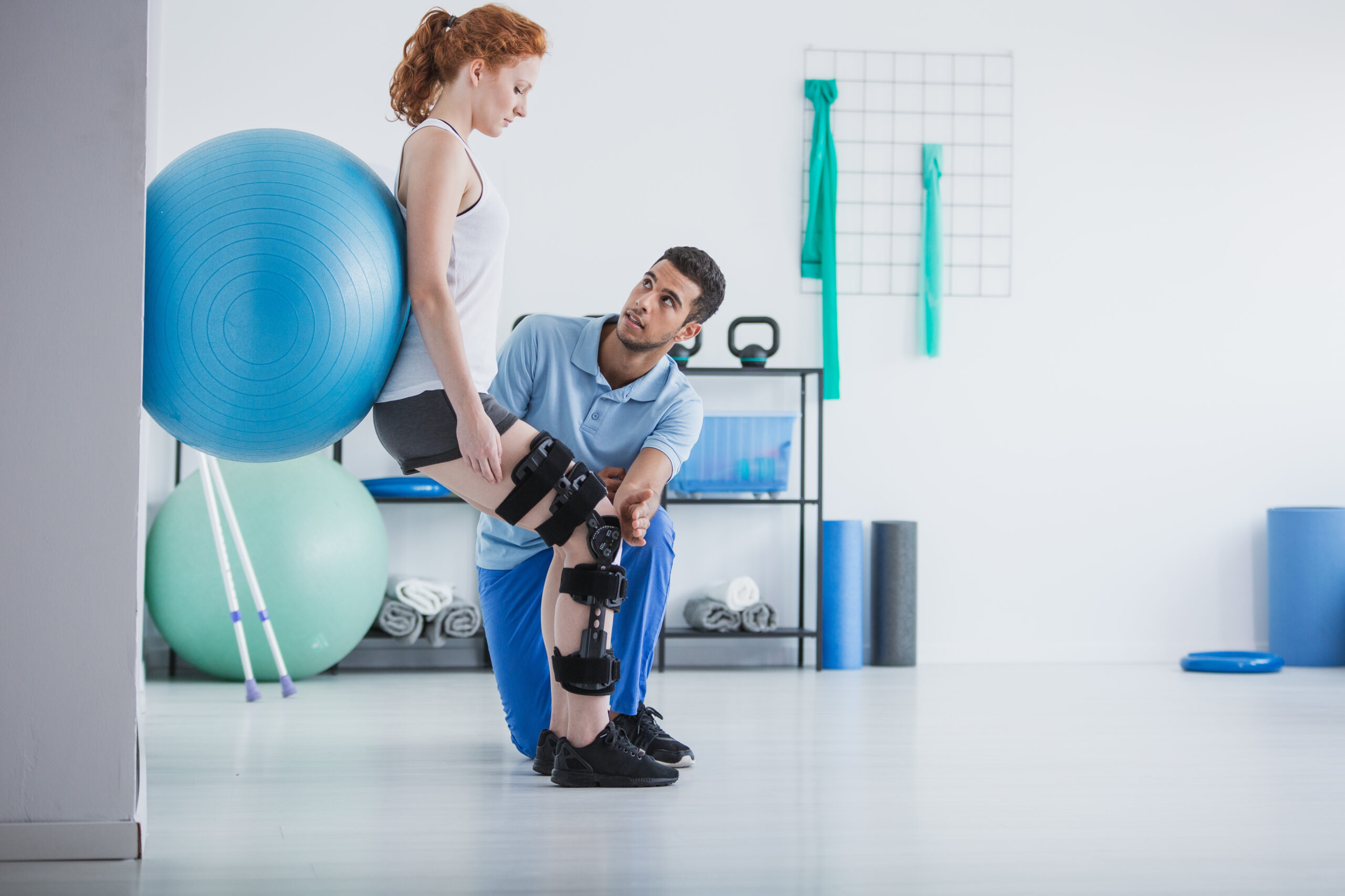 Post-operative physical therapy with a woman exercising on a ball under physiotherapist guidance.