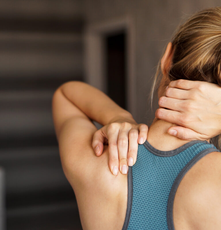 Young woman holding her neck in pain showing delayed neck pain or muscle strain from exercise.