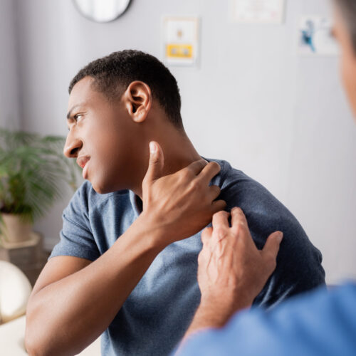 Doctor examining a patient’s neck to evaluate possible muscle or nerve pain.