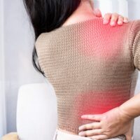 Woman experiencing shoulder and back pain spreading between areas, showing referred pain.
