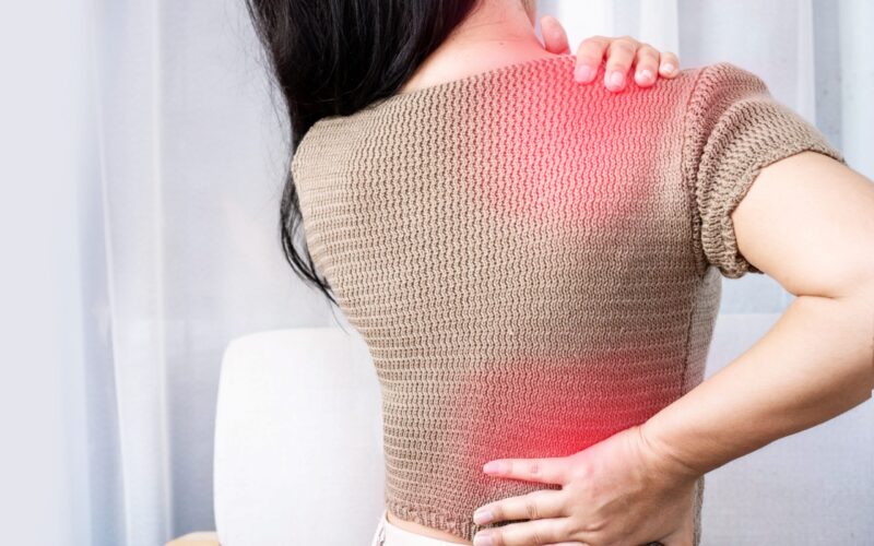 Woman experiencing shoulder and back pain spreading between areas, showing referred pain.
