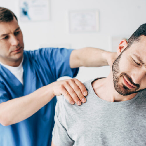 Specialist evaluating a man experiencing referred pain in the neck and shoulder.