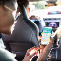 Woman seated inside a rideshare car checking her smartphone during an Uber ride.