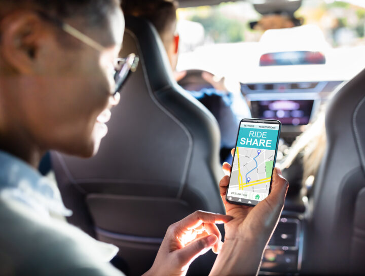 Woman seated inside a rideshare car checking her smartphone during an Uber ride.