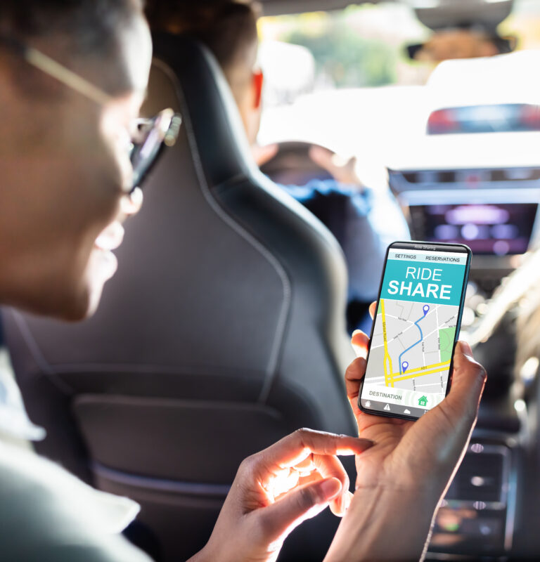 Woman seated inside a rideshare car checking her smartphone during an Uber ride.