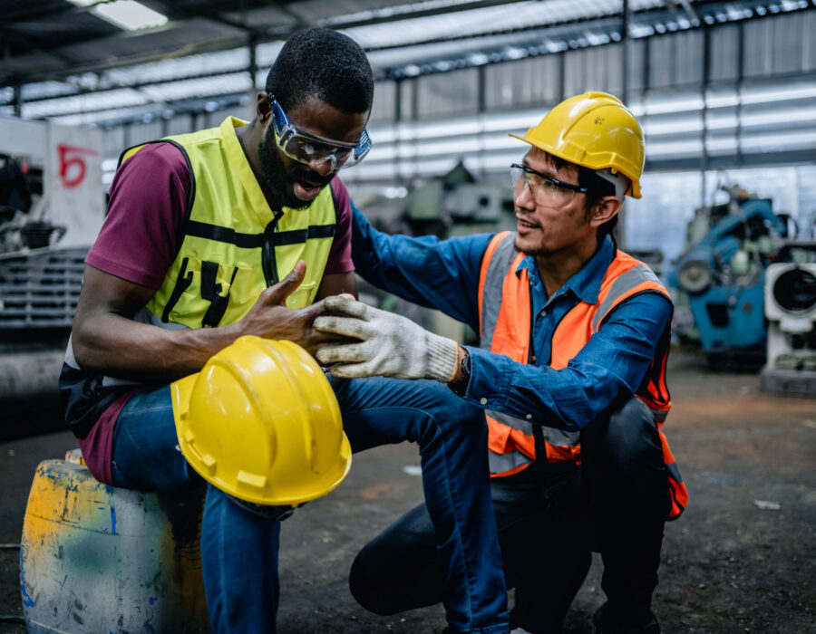 Construction worker receiving first aid for a finger injury after a job site accident, illustrating a common construction hand injury.