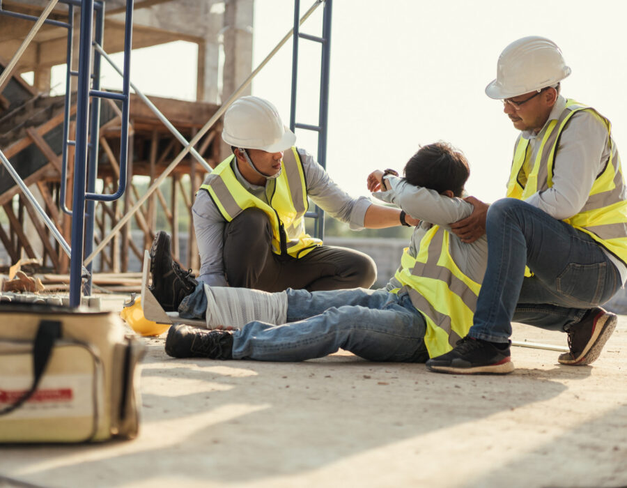 Construction worker who fell from scaffolding receiving assistance from coworkers after a construction site accident.