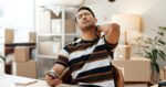 Man holding the back of his neck while looking at his phone at a desk, illustrating tech neck and neck pain from prolonged device use.
