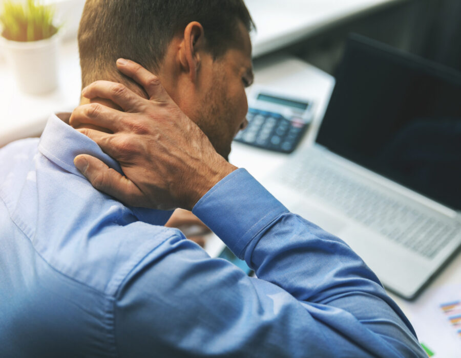 Office worker experiencing neck discomfort while sitting at a computer workstation, representing neck pain related to prolonged screen use and forward head posture.