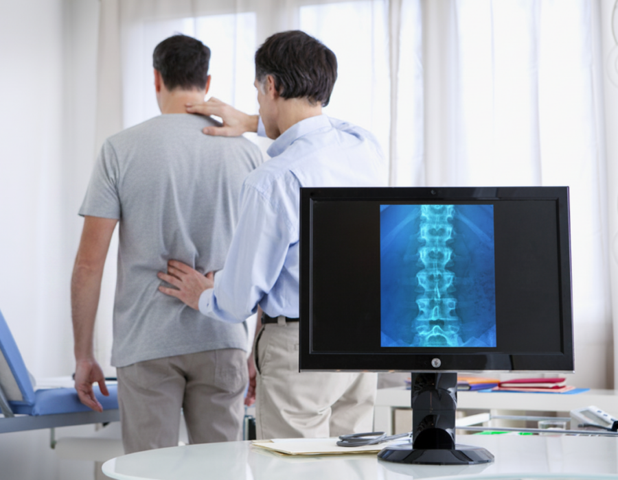 Patient consulting with a doctor about back pain and spinal nerve symptoms during a medical evaluation.