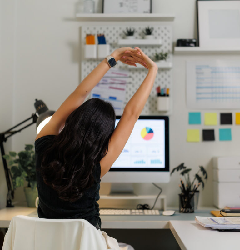 Remote worker stretching at a home office desk during a movement break while working from home