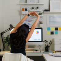 Remote worker stretching at a home office desk during a movement break while working from home