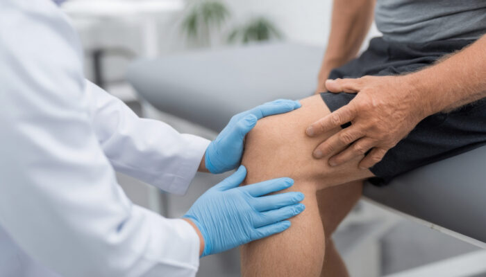 Medical professional evaluating knee pain during a patient examination.