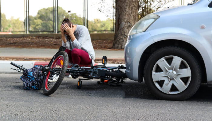 Woman holding her head after an ebike accident involving a car on a city street