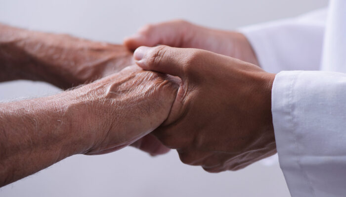 Doctor holding a patient’s hand during a rehabilitation and injury care consultation at Premier East PM&R.