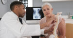 Physician explaining spinal anatomy and nerve pathways to a patient experiencing pinched nerve symptoms.