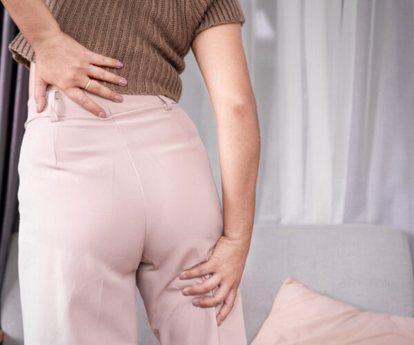 Nerve-Flossing-3 Woman holding her lower back and leg while experiencing symptoms associated with a pinched nerve or sciatica.