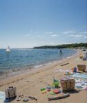 summer beach scene at Sunken Meadow State Park near Smithtown with paddle boarder and beach setup