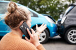 Person standing near vehicles after a collision on the phone, representing PTSD after a car accident