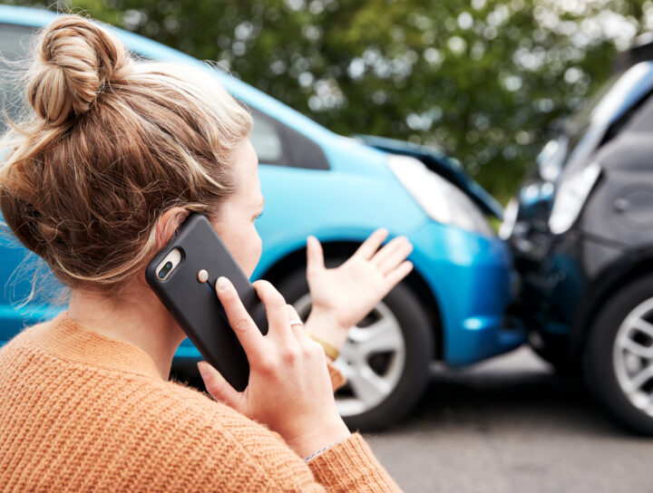 Person standing near vehicles after a collision on the phone, representing PTSD after a car accident