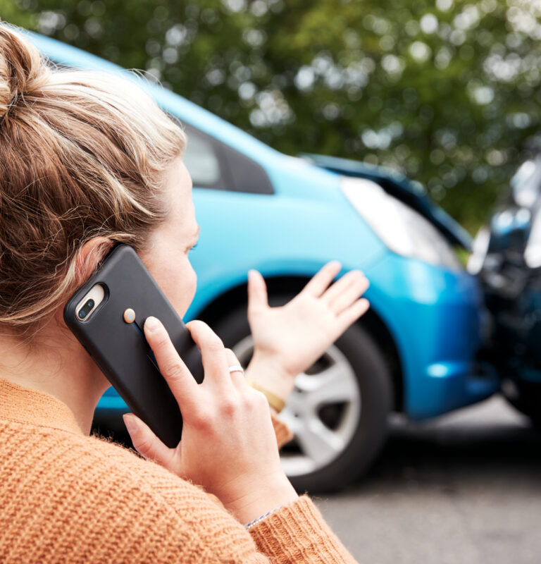 Person standing near vehicles after a collision on the phone, representing PTSD after a car accident