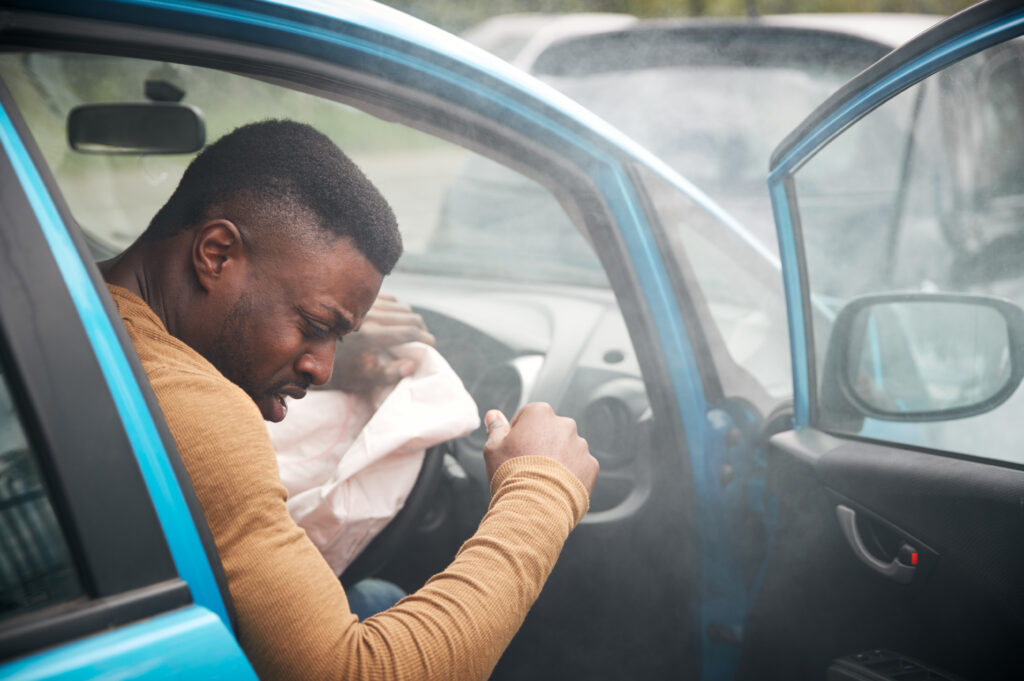 Driver experiencing pain after airbag deployment following a car accident, illustrating common airbag deployment injuries and post-crash symptoms.