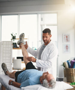 Physical therapist assessing a patient’s leg movement and lower-body function during injury rehabilitation.